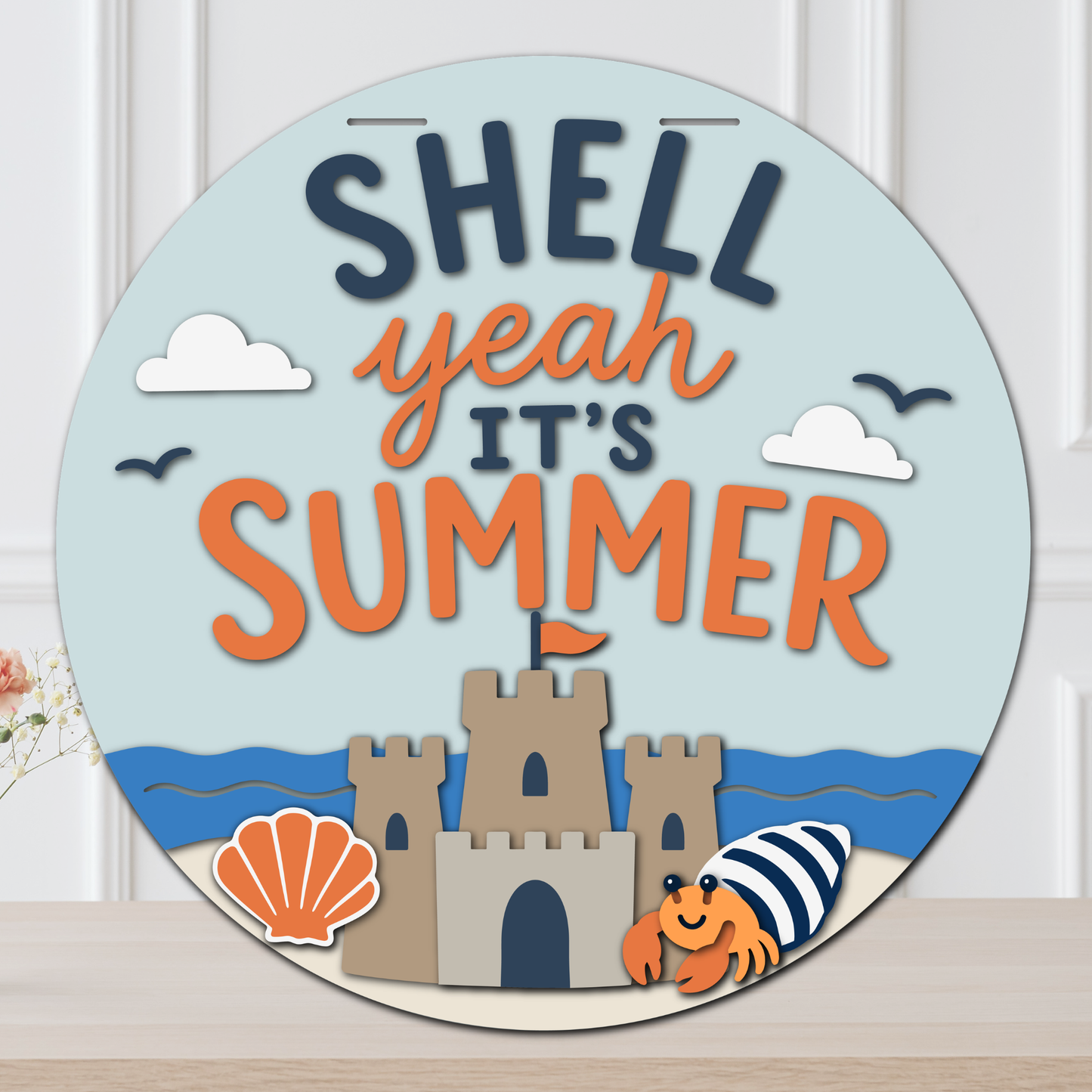 Layered summer door hanger with “Shell Yeah It’s Summer” lettering, beach waves, sandcastle, seashell, clouds, birds, and a hermit crab.