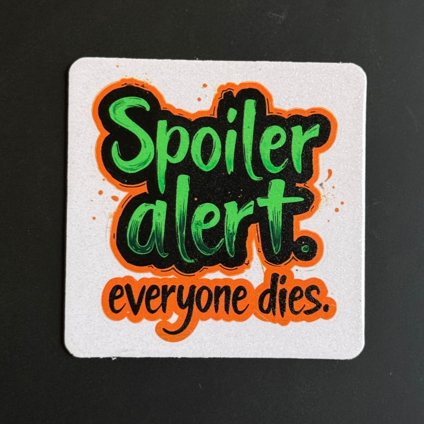 A square white coaster with rounded corners featuring the text 'Spoiler alert. everyone dies.