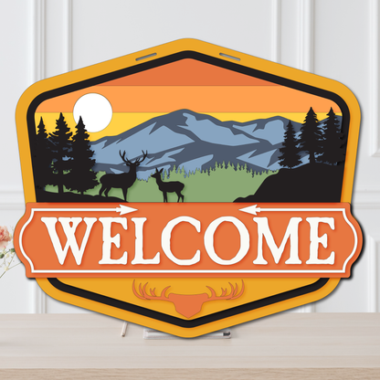 Decorative 'Welcome' sign with mountain and deer design on a white background