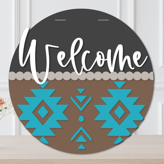 Round decorative sign with 'Welcome' text and blue geometric patterns on a wooden surface.