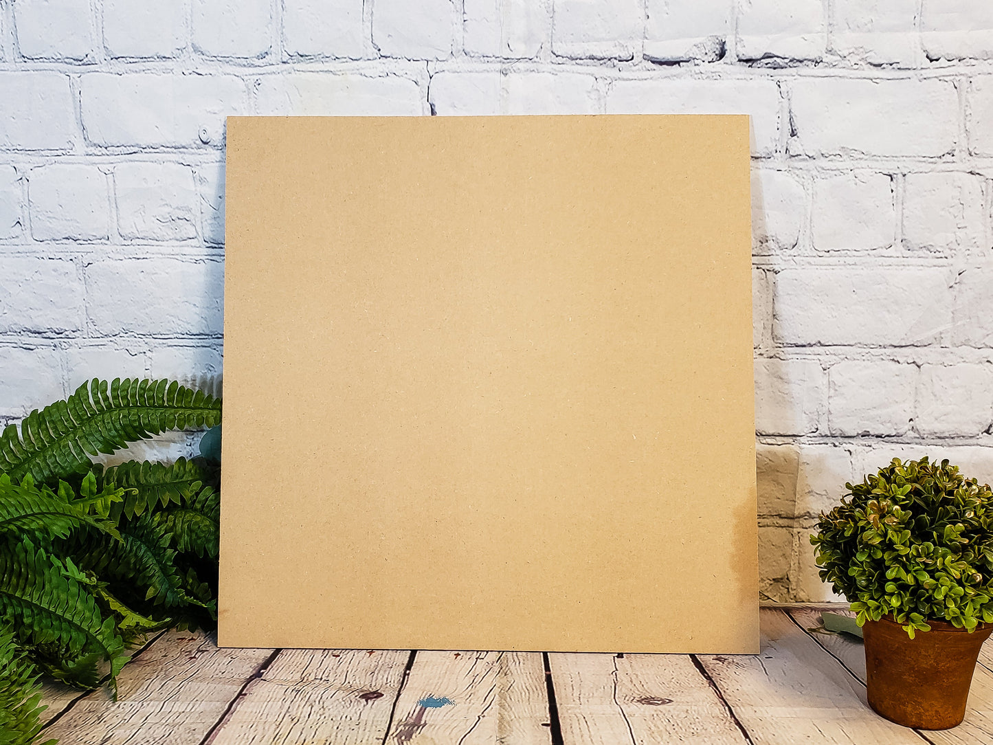 Raw MDF on a wooden floor with plants against a white brick wall