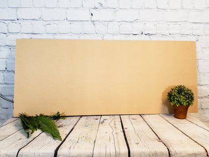 Large MDF sheet on a wooden surface with plants against a white brick wall.