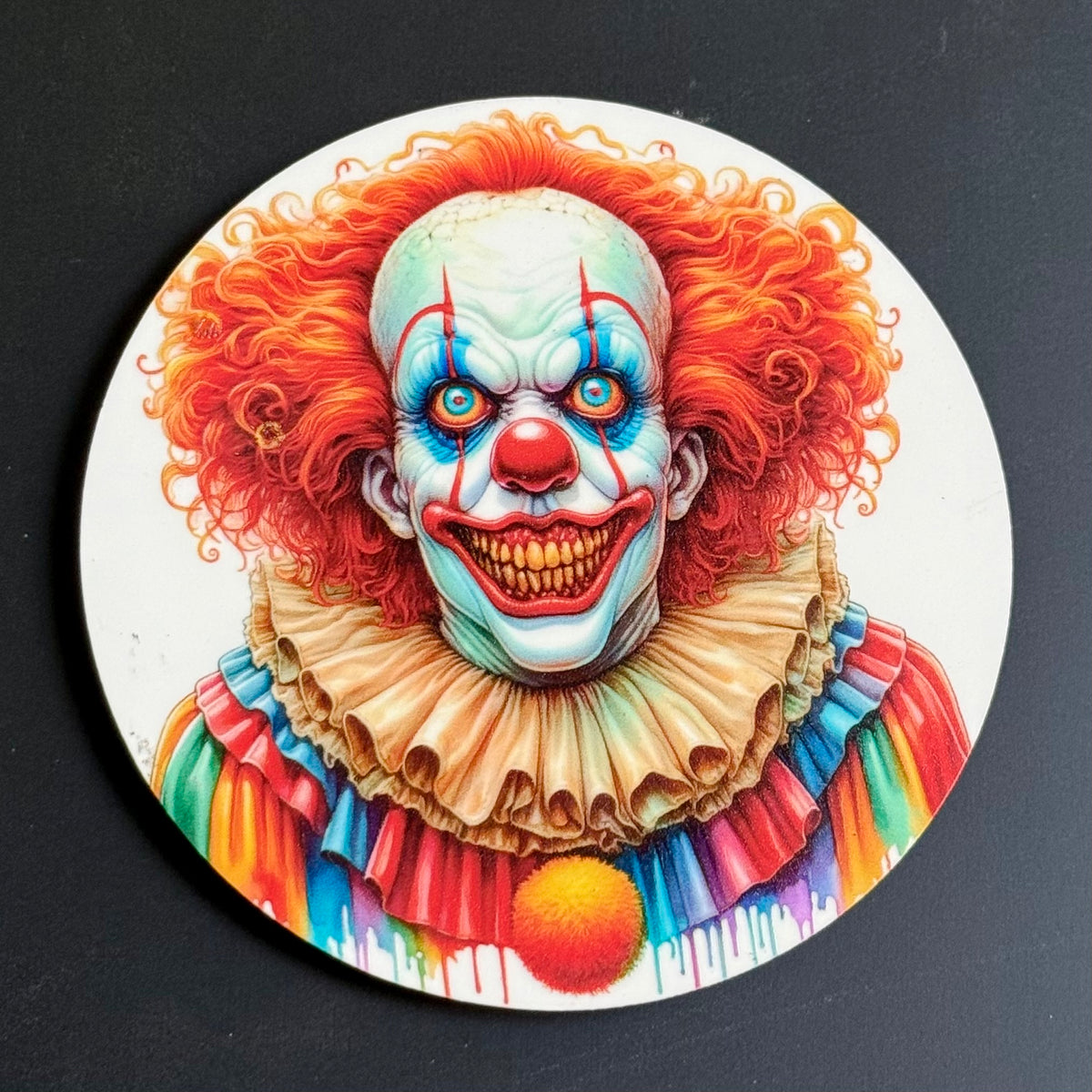 A circular coaster featuring a highly detailed illustration of a creepy clown with bright orange curly hair, blue face paint, a red nose, and a colorful rainbow ruffled collar, shown on a dark gray background.