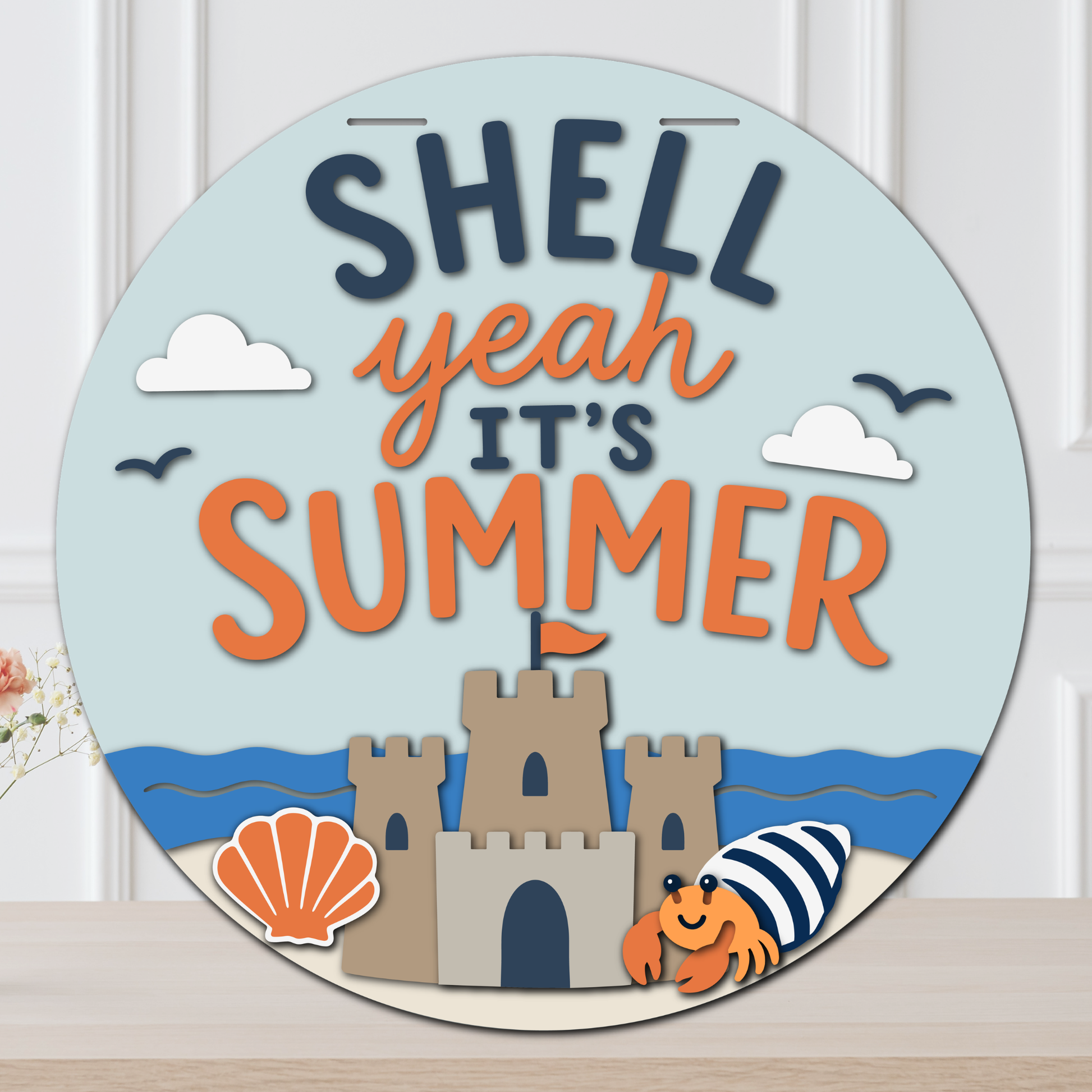 Layered summer door hanger with “Shell Yeah It’s Summer” lettering, beach waves, sandcastle, seashell, clouds, birds, and a hermit crab.