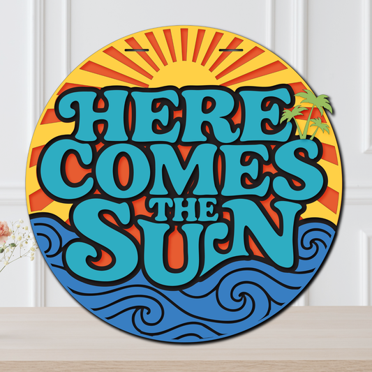 Decorative sign with 'Here Comes the Sun' text and sun design on a white background