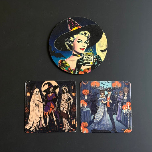 Three Halloween-themed printed coasters arranged on a dark surface: one round coaster at the top featuring a witch with a potion bottle, and two rectangular coasters below with gothic horror illustrations.