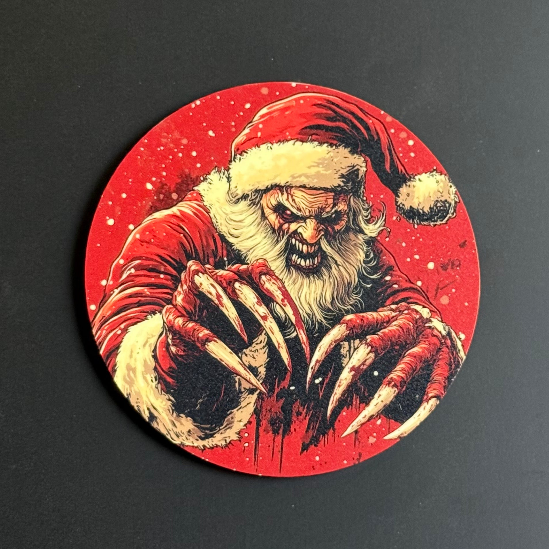 A circular coaster featuring a horror-themed illustration of a menacing Santa Claus with long claws and a blood-splattered red background, shown on a dark surface.