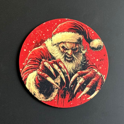A circular coaster featuring a horror-themed illustration of a menacing Santa Claus with long claws and a blood-splattered red background, shown on a dark surface.