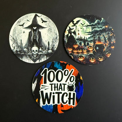 Three round Halloween-themed coasters displayed on a dark background. One coaster features a black and white witch and skull design under a full moon.
