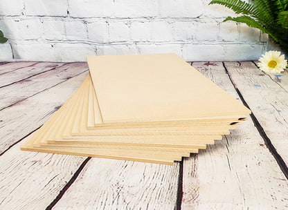 Stack of MDF on a wooden surface with a white brick wall and plant in the background
