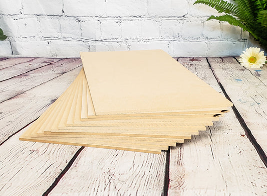 Stack of MDF on a wooden surface with a white brick wall and plant in the background