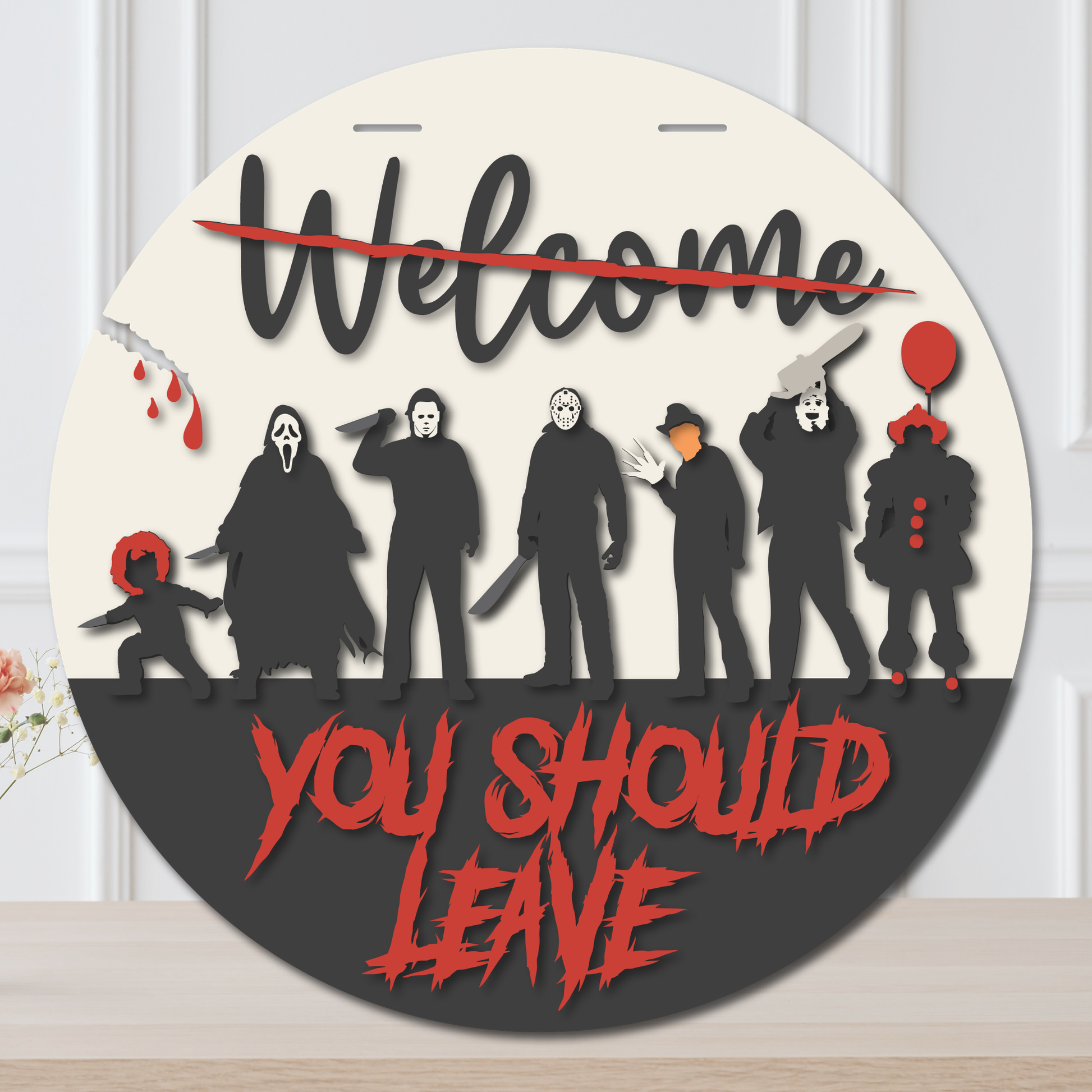 Layered horror Halloween door hanger with creepy figures, slashed Welcome lettering, blood details, and red You Should Leave text