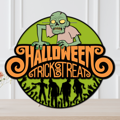 Layered Halloween door hanger featuring a creepy green zombie, orange Trick or Treat lettering, zombie silhouettes, and reaching hands.